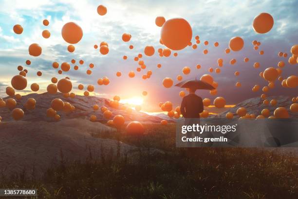 surreal image of man standing in the field with falling spheres - balls bouncing stock pictures, royalty-free photos & images