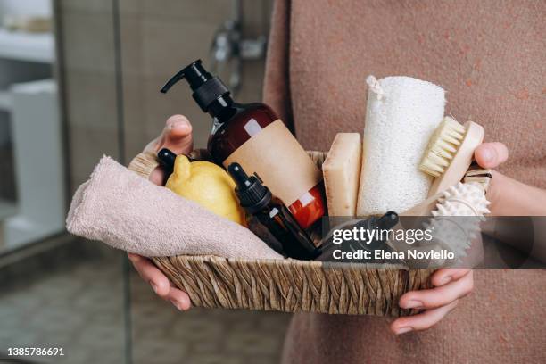 body and face care beauty bath set. lotion, essential oil, cream, massage brushes and anti-cellulite in a basket in the hands of a young woman. - lichaamsverzorging stockfoto's en -beelden