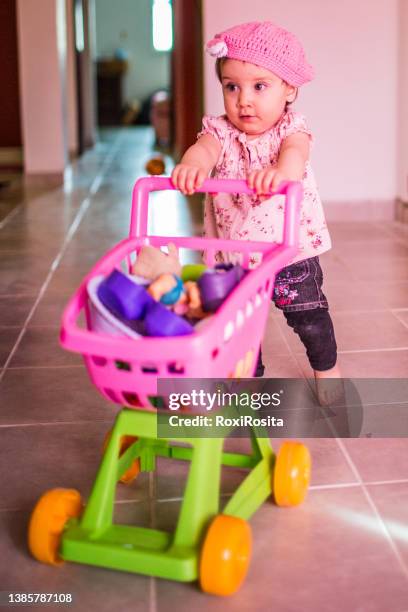 nice little girl carrying a toy supermarket cart - baby products stock pictures, royalty-free photos & images