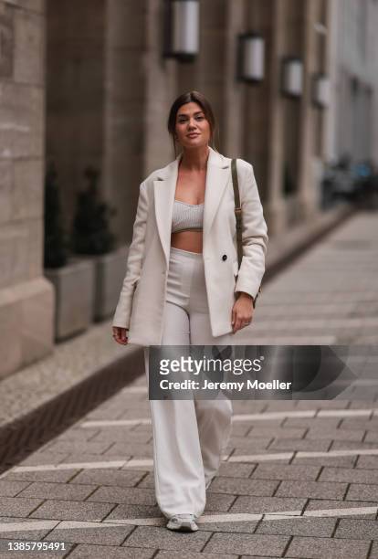 Nadine Klein seen wearing gold earrings, a black sunglasses, a creme white oversized blazer, a beige knit bralette, a creme white wide leg trousers,...