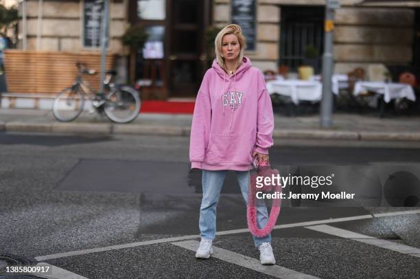 Palina Kozyrava is wearing a Balenciaga Gay Pride oversized rose sweater, Zara blue jeans, white Fila chunky sneaker, Balenciaga pink fluffy...
