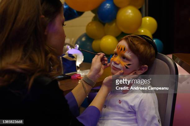 Boy who fled the conflict in Ukraine gets a face painting at a Purim celebration, on March 16, 2022 in Chisinau, Moldova. Among the more than 3...