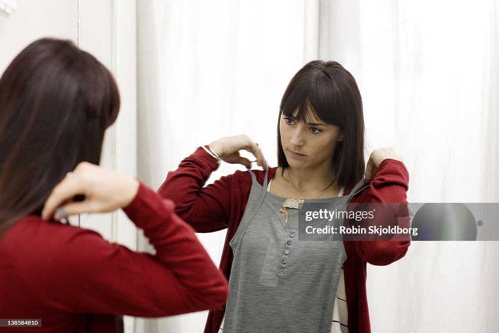 Girl in clothes shop looking at clothes in mirror