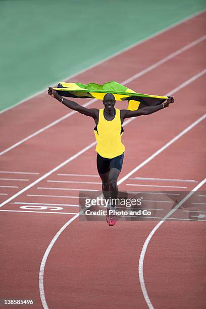 runner celebrating with jamaica flag on track - mens track photos et images de collection