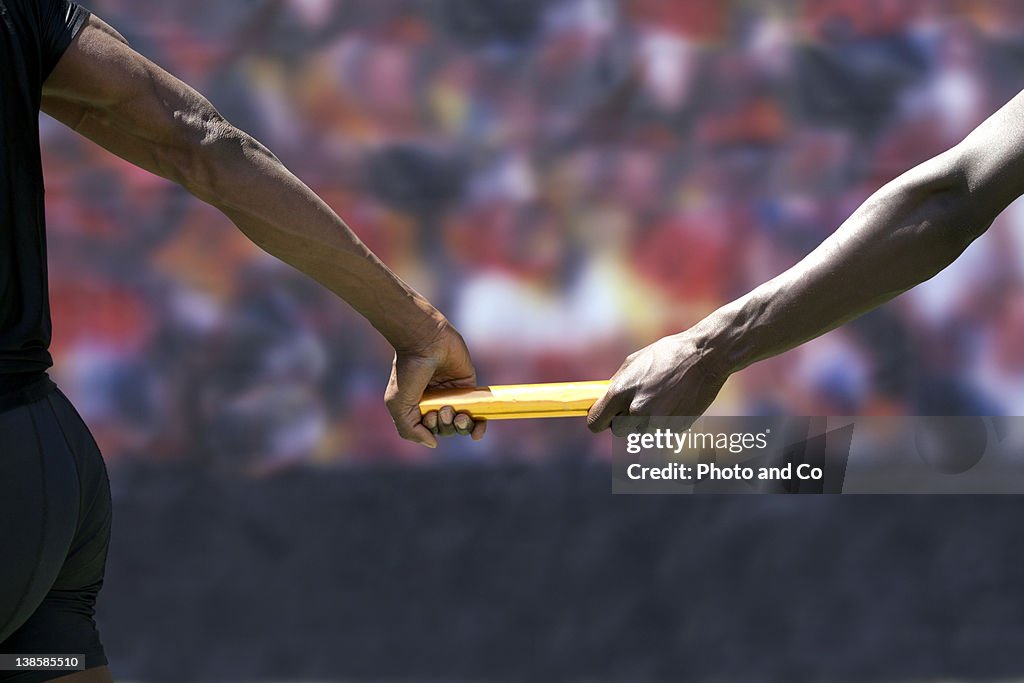 Two male runners passing baton