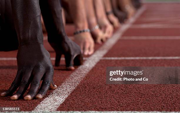 track sprinters lined up at starting line - sprinting stock-fotos und bilder