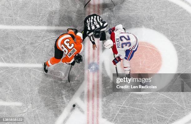 Linesman Kory Nagy watches Patrick Brown of the Philadelphia Flyers win control of the puck on a face-off against Rem Pitlick of the Montreal...