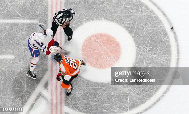Linesman Kory Nagy watches Claude Giroux of the Philadelphia Flyers win control of the puck on a face-off against Jake Evans of the Montreal...