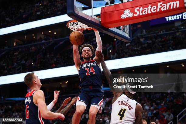 Corey Kispert of the Washington Wizards dunks in front of DeMarcus Cousins of the Denver Nuggets during the second half at Capital One Arena on March...