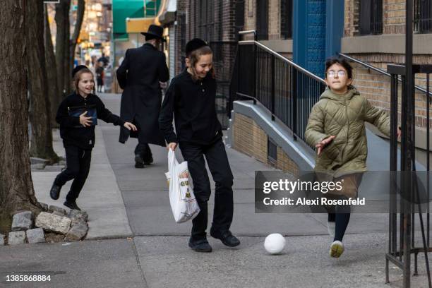 Ultra-Orthodox Jewish children play with a ball ahead of Purim in Williamsburg on March 16, 2021 in the Brooklyn borough of New York City. Purim...