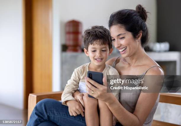 boy at home watching videos online with his mother - family looking at smartphone stockfoto's en -beelden