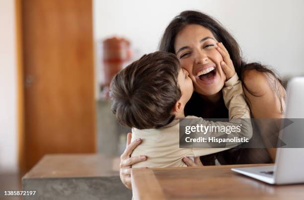 loving son giving a kiss to her mother while she is working at home - mama stock pictures, royalty-free photos & images