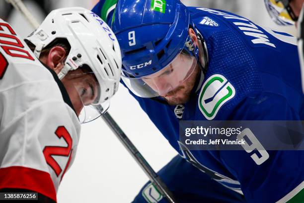 New Jersey Devils' Jack Hughes, front, and his brother, Vancouver Canucks' Quinn Hughes, watch a play during the second period of an NHL hockey game Tuesday, March 15, 2022, in Vancouver, British