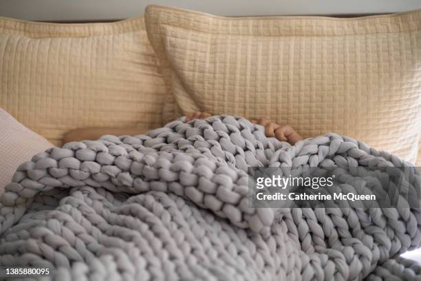unrecognizable female under weighted blanket in bed - blanket photos et images de collection