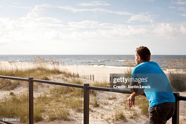 young man gazing out over the beach and ocean - gulf coast states stock pictures, royalty-free photos & images