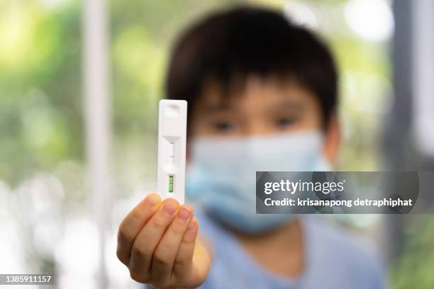 boy holding rapid antigen test kit with positive result during swab covid-19 testing. coronavirus self nasal or home test, lockdown and home isolation concept - epidemiology icon stock pictures, royalty-free photos & images