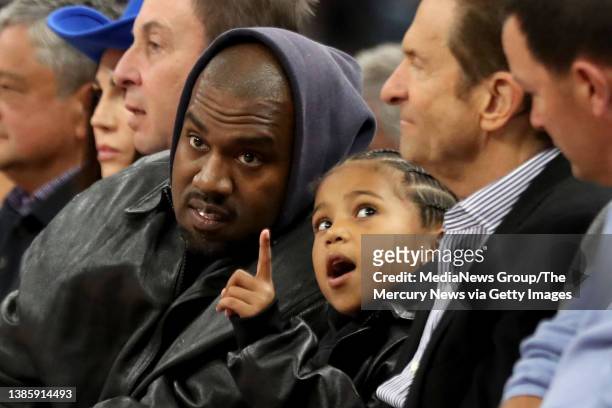 Kanye West, center, and his son, Saint West, got front row seats next to Golden State Warriors co-owners Joe Lacob and Peter Guber as they watch the...