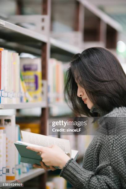 図書館の本棚から本を選ぶアジアの女子学生 - 文学 ストックフォトと画像