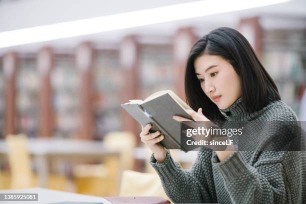 estudiantes asiáticas están leyendo en la biblioteca, frente a la estantería - windmill books fotografías e imágenes de stock