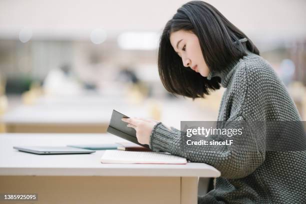 estudiantes asiáticas están leyendo en la biblioteca, frente a la estantería - windmill books fotografías e imágenes de stock