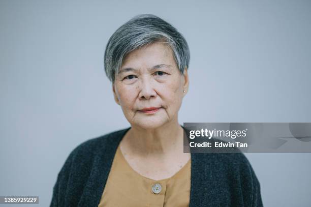 portrait asian chinese senior woman looking at camera serious face with white background - asian woman face imagens e fotografias de stock