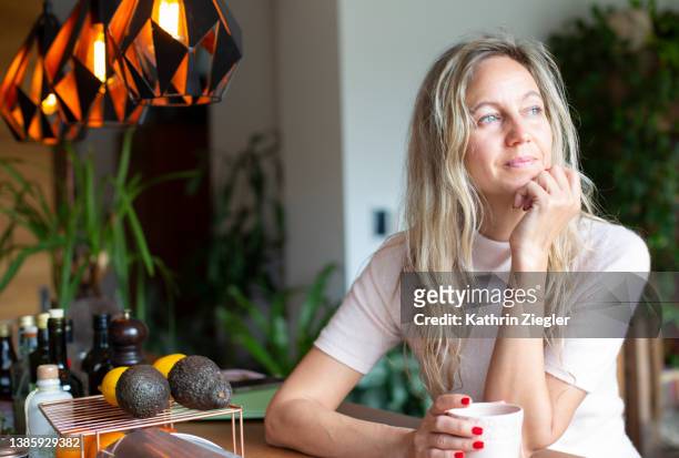 contemplative woman having a cup of tea - 40 year old woman blonde blue eyes stock pictures, royalty-free photos & images