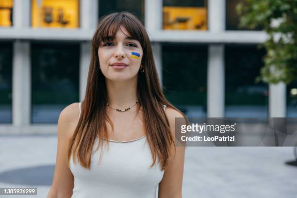 portrait of a young woman with a ukrainian flag on face - faces of the conflict stock pictures, royalty-free photos & images