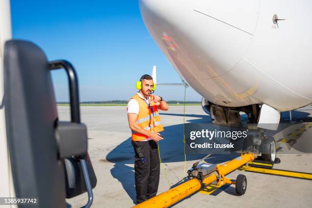 bodencrew schleppt flugzeug zur landebahn zum abflug - airport ground crew uniform stock-fotos und bilder