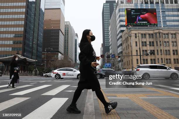 People walk along the street on March 17, 2022 in Seoul, South Korea. South Korea's new daily COVID-19 cases spiked to more than 600,000 on Thursday,...