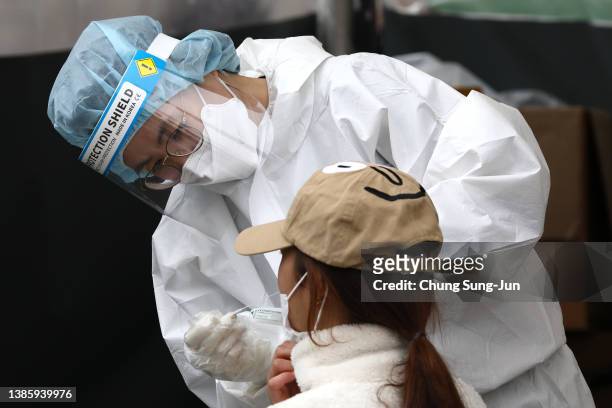 Medical staff member takes samples from people at a preliminary testing center on March 17, 2022 in Seoul, South Korea. South Korea's new daily...