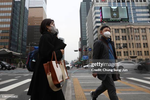 People walk along the street on March 17, 2022 in Seoul, South Korea. South Korea's new daily COVID-19 cases spiked to more than 600,000 on Thursday,...