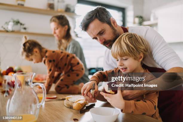 young family with two little children preparing breakfast together in kitchen. - famiglia con due figli foto e immagini stock