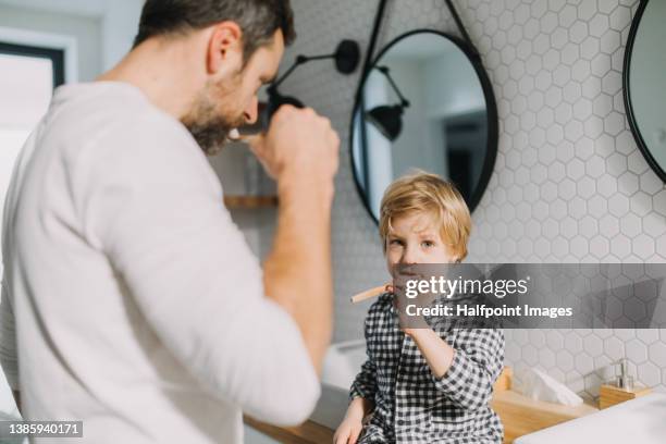father with small child indoors in bathroom in the morning at home, brushing teeth. - dental bonding stock pictures, royalty-free photos & images