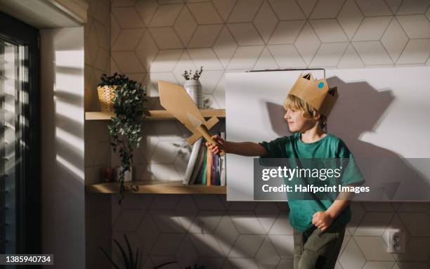 little child in king costumes playing with cardboard sword at home. - koning koninklijk persoon stockfoto's en -beelden