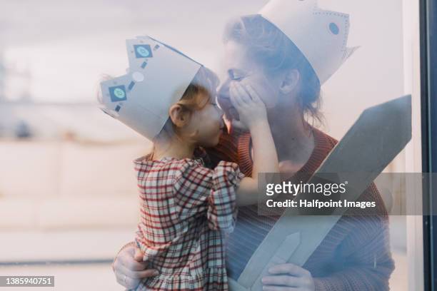 mother with little child in kings costumes playing together at home, shot through glass. - photographed through window stock pictures, royalty-free photos & images