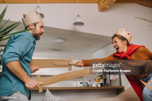 parents in knights' costumes having fun and playing with diy swords together at home. - knight person stock pictures, royalty-free photos & images