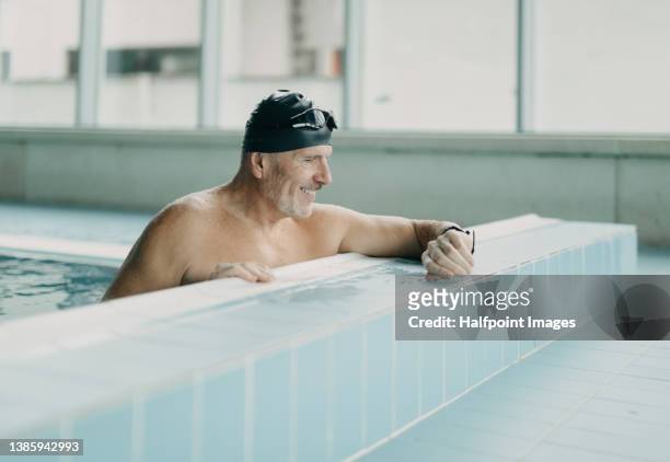 active senior man swimmer holding onto starting block in indoors swimming pool. - backstroke fotografías e imágenes de stock