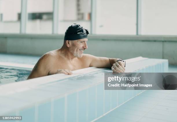 active senior man swimmer holding onto starting block in indoors swimming pool. - backstroke stock pictures, royalty-free photos & images