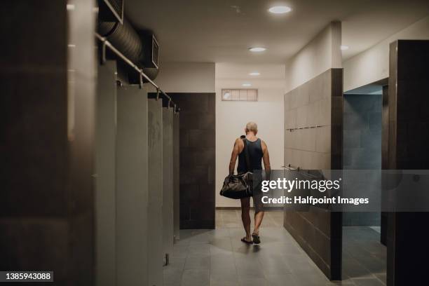 rear view of senior man swimmer preparing for swim indoors in public swimming pool. - locker stockfoto's en -beelden