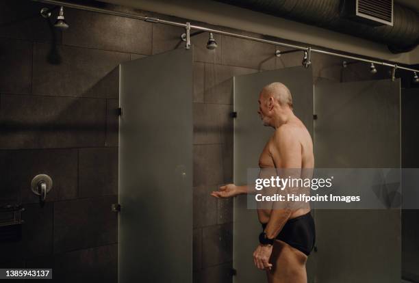 senior man swimmer preparing for swim indoors in public swimming pool. - bath shower stock pictures, royalty-free photos & images