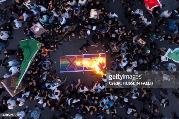 Supporters of Iraq's Sadrist movement burn an Israeli and a rainbow flag during a rally in Basra on July 2 amid protests against a Koran burning...