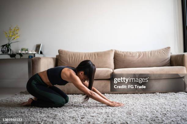 mid adult woman stretching at home - bend over woman stock pictures, royalty-free photos & images