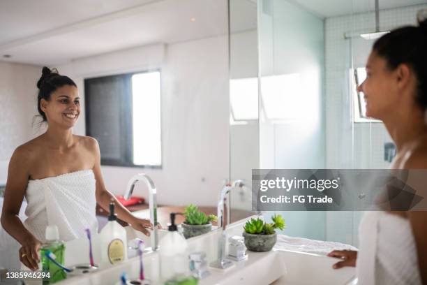 happy woman looking in the mirror at home - bathroom mirror 個照片及圖片檔