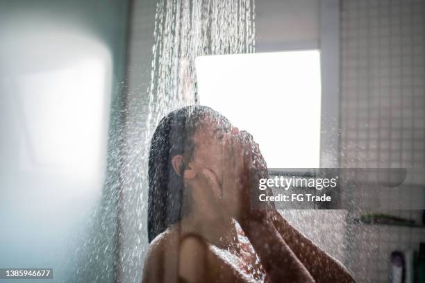 femme prenant une douche à la maison - douche photos et images de collection
