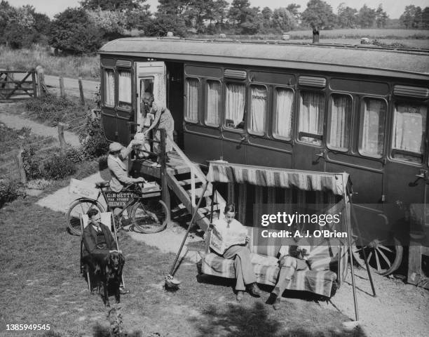 The bicycle delivery boy from G&M Betty Stores, Redwick, drops off a delivery at the railway carriage home of the Hodgkins family, with people...