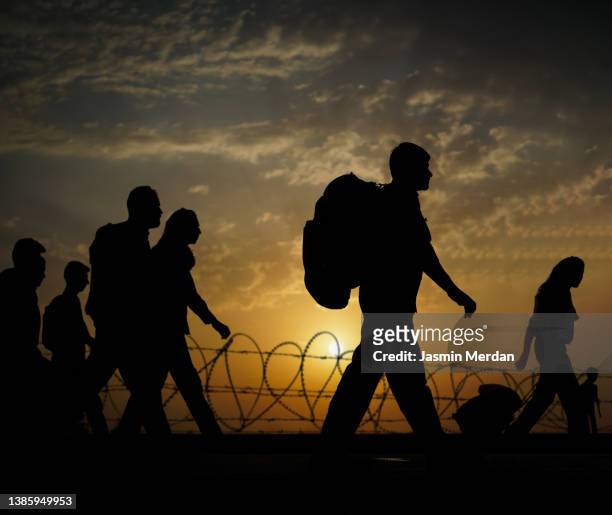 column of migrants walking to the border, immigration crisis - arab woman silhouette stock pictures, royalty-free photos & images