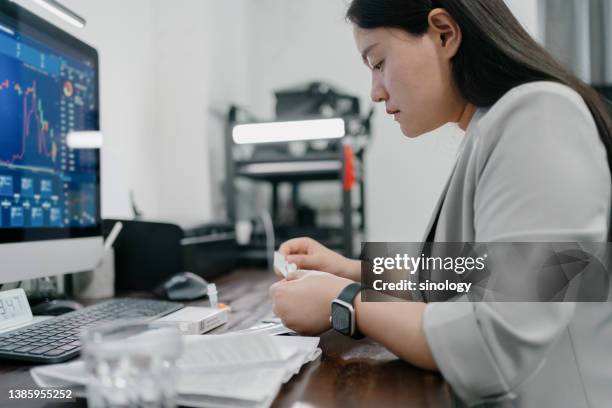 asian woman using covid rapid test in home - infection prevention stockfoto's en -beelden