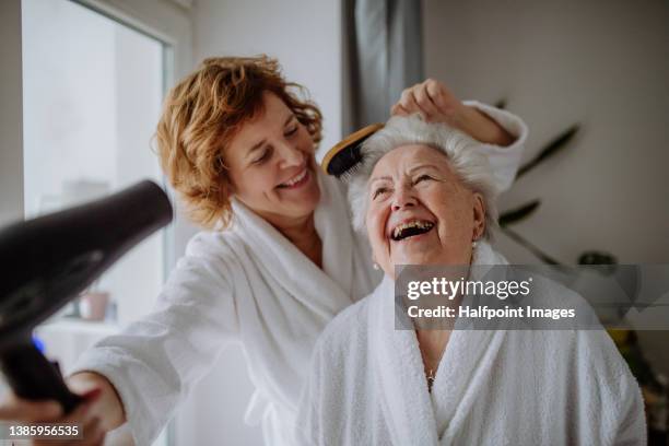 senior mother with mature daughter in bathrobes having spa day at home together. - lichaamsverzorging stockfoto's en -beelden