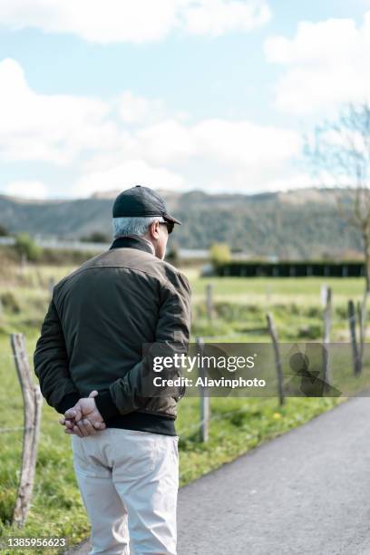 middle-aged man with gray hair, sunglasses and cap walking in a rural area in the countryside. - de ascendencia europea 個照片及圖片檔