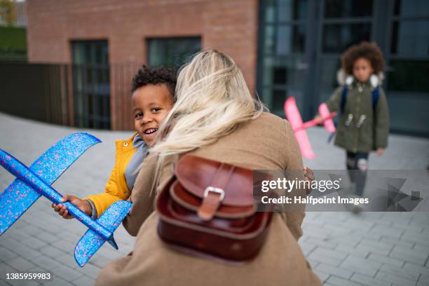 happy little multiracial siblings running to their mother waiting for them after school outdoors in street. - mother running stockfoto's en -beelden